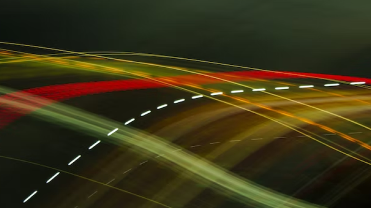 Dynamic image capturing the essence of speed and energy efficiency in VREMT electric drive technology, depicted through vibrant streaks of red and yellow lights against a dark background, symbolizing the fast and powerful performance of VREMT’s electric batteries on the road